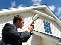 Inspector examining a house exterior with a magnifying glass